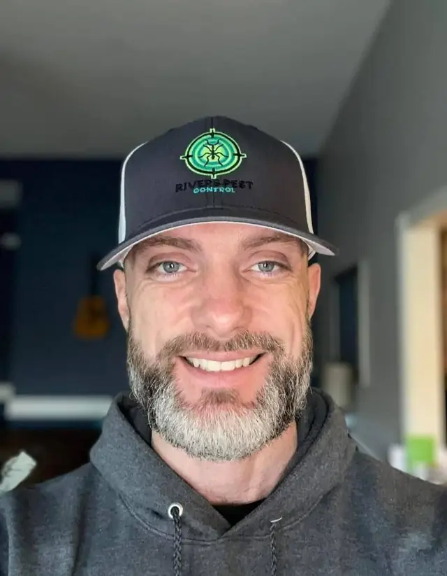 A grey-bearded Rivers technician in a company cap taking a selfie