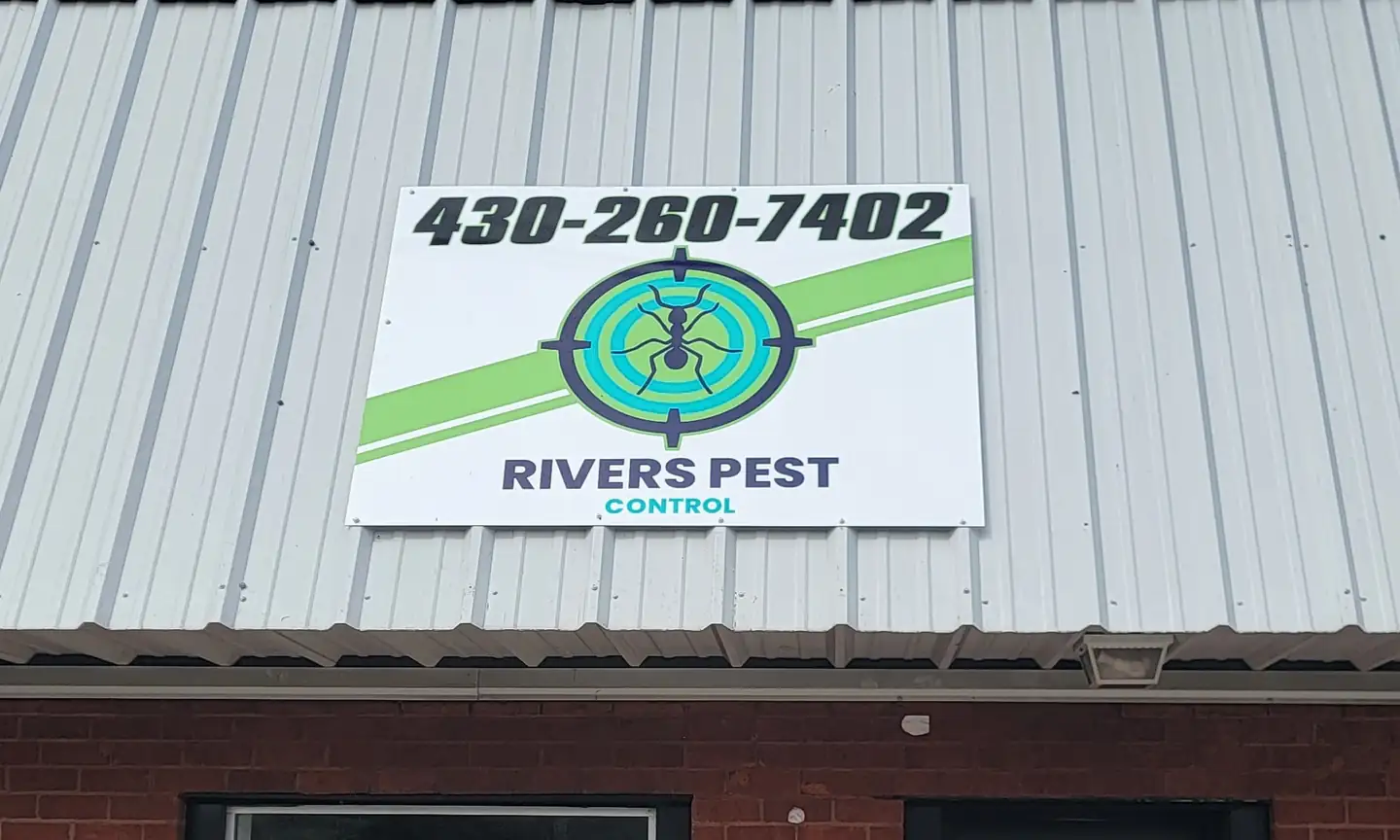 The Rivers Pest Control sign, with the phone number and crosshair-ant logo, over their storefront on South Main in Lindale