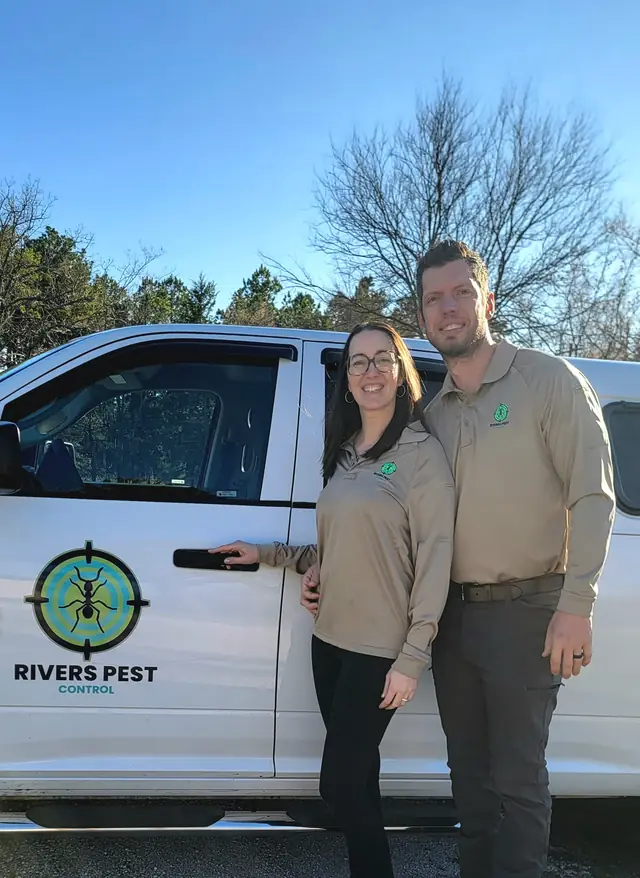 A man and a woman in tan Rivers company polos standing at a truck door