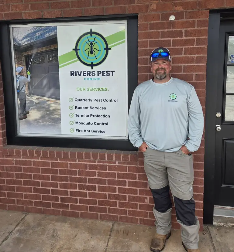 A Rivers technician standing beside the services poster at the storefront